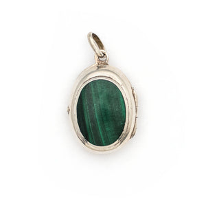 This oval sterling silver vintage locket features banded dark green malachite at its center with a beautifully etched leafed design on the back . It opens to hold two photos and pairs perfectly with one of our antique sterling silver chains. Front locket view