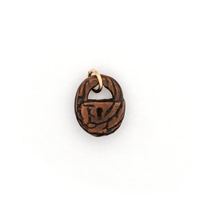 This unique lock charm is carved out of walnut wood and has intricate carving details along the surface and a "key hole." Paired with one of our vintage gold fill chains, this rare charm can be worn both as a alone as a pendant or in a cluster of charms. Front charm view