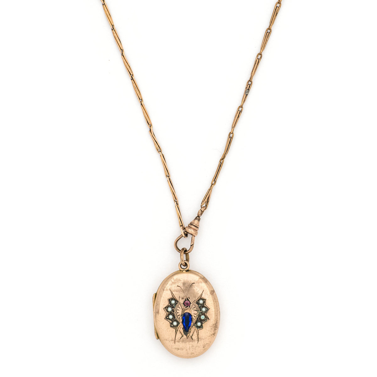 This unique oval Victorian locket features blue and red stones and seed pearls set within a finely etched bug design. It opens to hold one photo, and pairs perfectly with one of our antique gold fill chains.  Front locket view