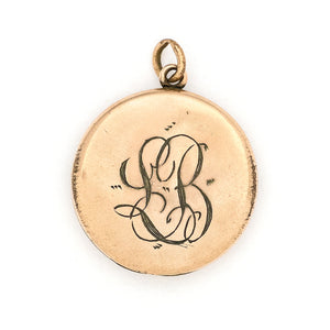 This round, matte locket features a starburst at the its center with a gorgeous border in Art Deco style and white paste stones throughout the design. It opens to hold one photo, includes one original frame and pairs perfectly with one of our antique gold fill chains.  Back locket view, showing monogram, LB