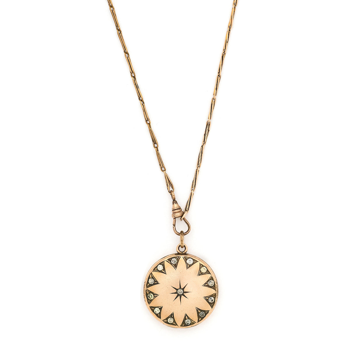 This round, matte locket features a starburst at the its center with a gorgeous border in Art Deco style and white paste stones throughout the design. It opens to hold one photo, includes one original frame and pairs perfectly with one of our antique gold fill chains.  Front locket view