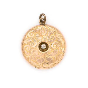 This romantic round Edwardian locket features a playful swirling pattern framing a sizable white paste stone at its center, and a polished verso.  It opens to hold two photos, includes both original frames and pairs perfectly with one of our antique gold fill chains.  Front locket view
