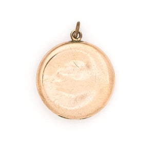 This romantic round Edwardian locket features a playful swirling pattern framing a sizable white paste stone at its center, and a polished verso.  It opens to hold two photos, includes both original frames and pairs perfectly with one of our antique gold fill chains.  Back locket view