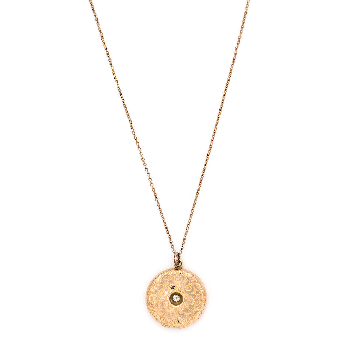 This romantic round Edwardian locket features a playful swirling pattern framing a sizable white paste stone at its center, and a polished verso.  It opens to hold two photos, includes both original frames and pairs perfectly with one of our antique gold fill chains.  Front locket view, shown on chain