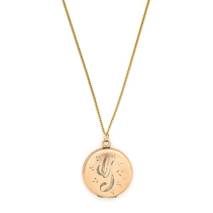This round locket features a beautifully stylized cursive "G", complete with accenting flourishes. It opens to hold two photos, includes both original frames and pairs perfectly with one of our antique gold fill chains. Front locket view, shown on chain