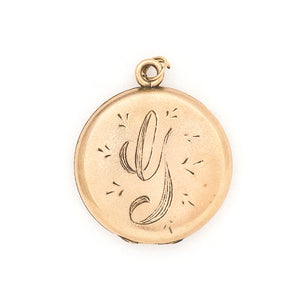 This round locket features a beautifully stylized cursive "G", complete with accenting flourishes. It opens to hold two photos, includes both original frames and pairs perfectly with one of our antique gold fill chains. Front locket view