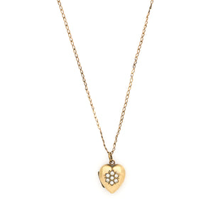 This sweet vintage heart-shaped locket features seven white glass stones in the shape of a snowflake with an intricate forget-me-not design on the back. It opens to hold one photo, includes one original frame and pairs perfectly with one of our antique gold fill chains. Front locket view, shown on chain