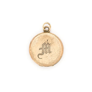 This petite round locket features a simple "M" in Old English script. It opens to hold two photos, includes both original frames and pairs perfectly with one of our antique gold fill chains. Front locket view