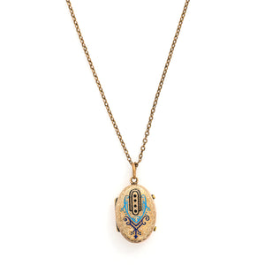 This unique oval locket features a delicate design with sky, navy blue and black enamel set on a finely textured background. The background features floral accents and a cross bar in the same instricate style. It opens to hold two photos, includes both original frames and glass and pairs perfectly with one of our antique gold fill chains.  Front locket view, shown on chain