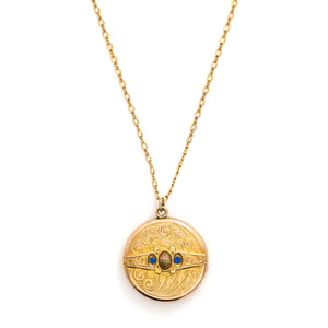 This detailed round locket features an intricate pattern reminiscent of rolling waves with two blue and one multicolored glass stones at it's center. It opens to hold two photos and pairs perfectly with one of our antique gold fill chains.  Front locket view, shown on chain