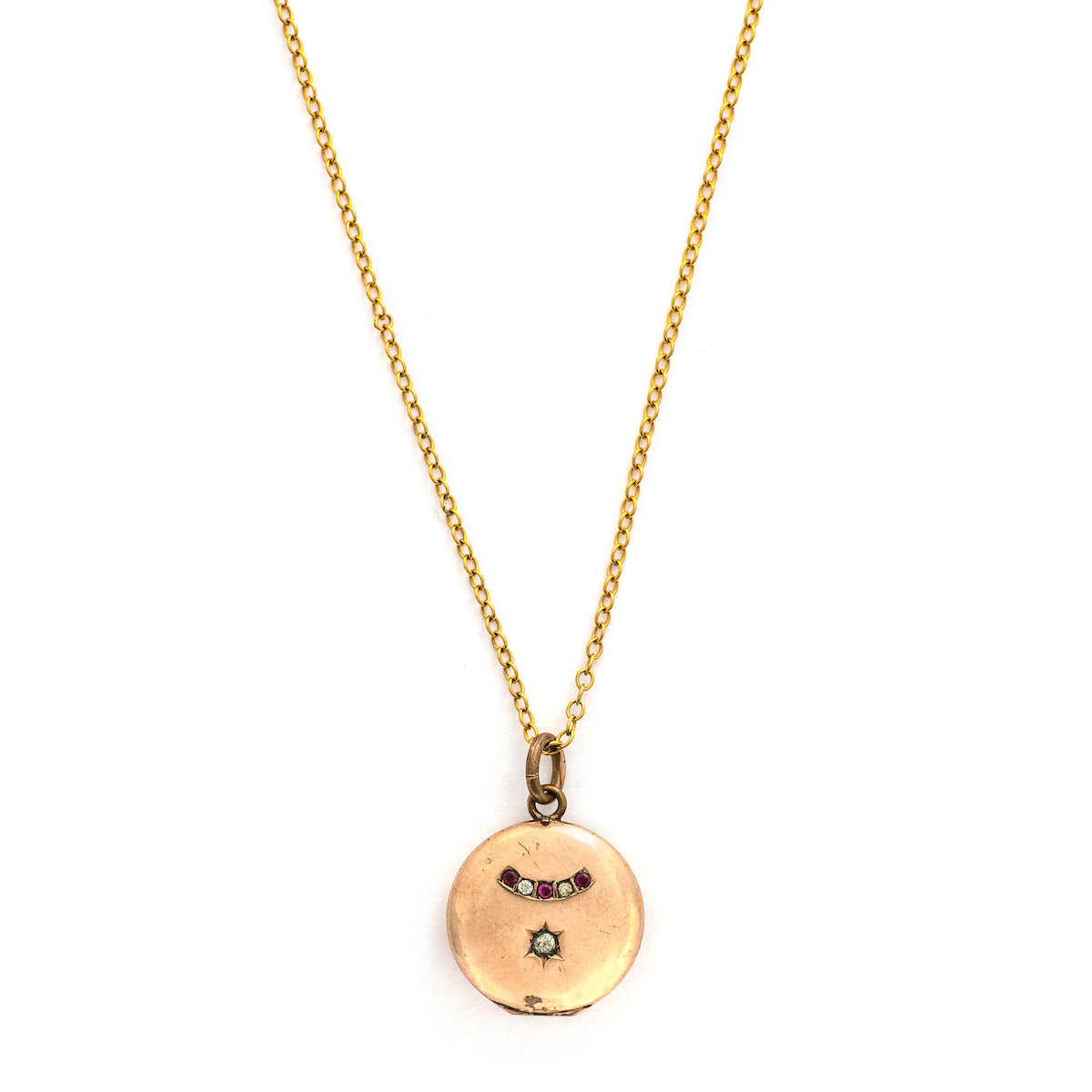 This petite round locket features red and white stones in an alternating pattern and a larger white stone at the center of a star. It opens to hold one photo and pairs perfectly with one of our antique gold fill chains.  Locket only