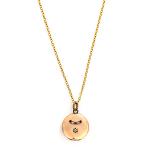 This petite round locket features red and white stones in an alternating pattern and a larger white stone at the center of a star. It opens to hold one photo and pairs perfectly with one of our antique gold fill chains.  Front locket view, shown on chain