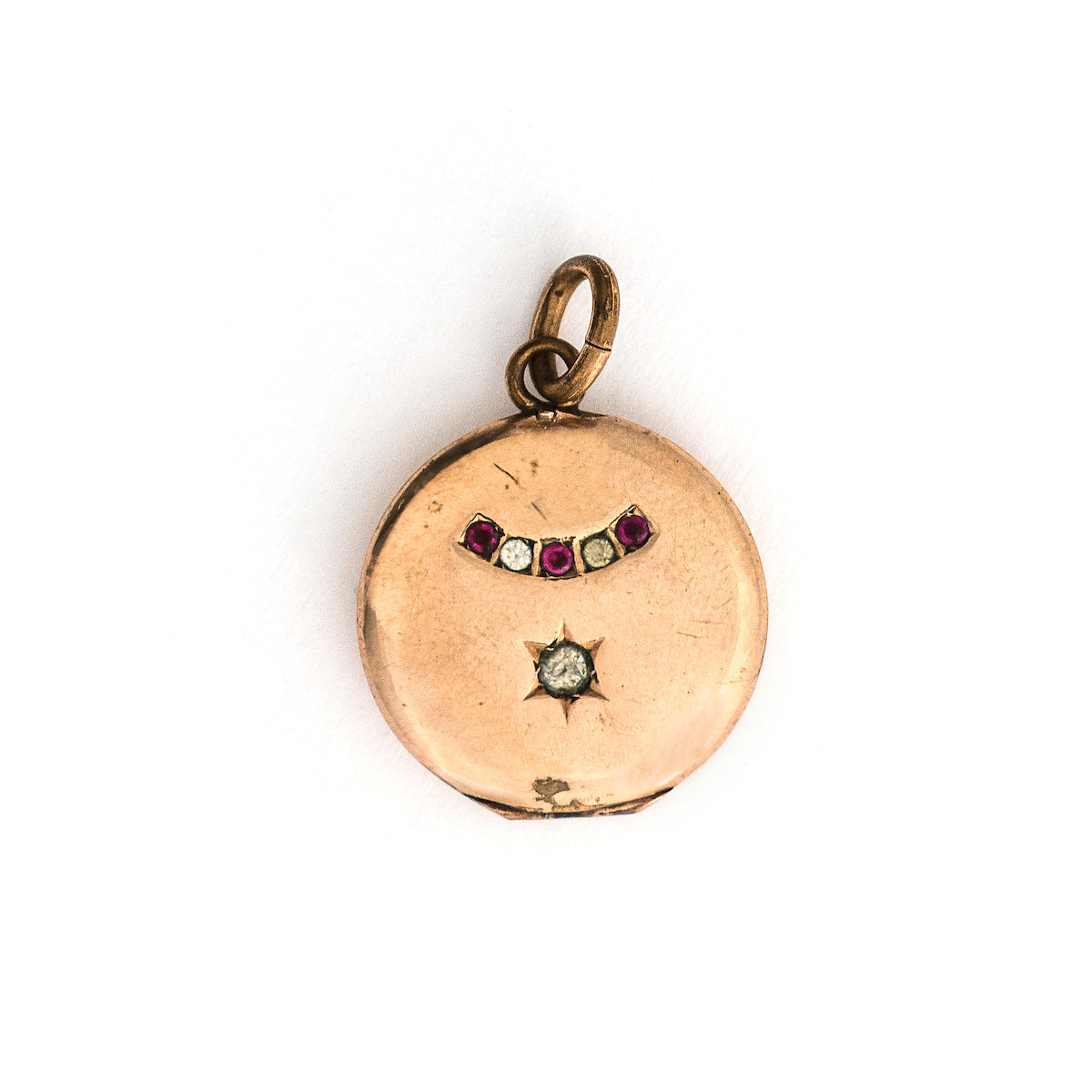 This petite round locket features red and white stones in an alternating pattern and a larger white stone at the center of a star. It opens to hold one photo and pairs perfectly with one of our antique gold fill chains.  Locket only