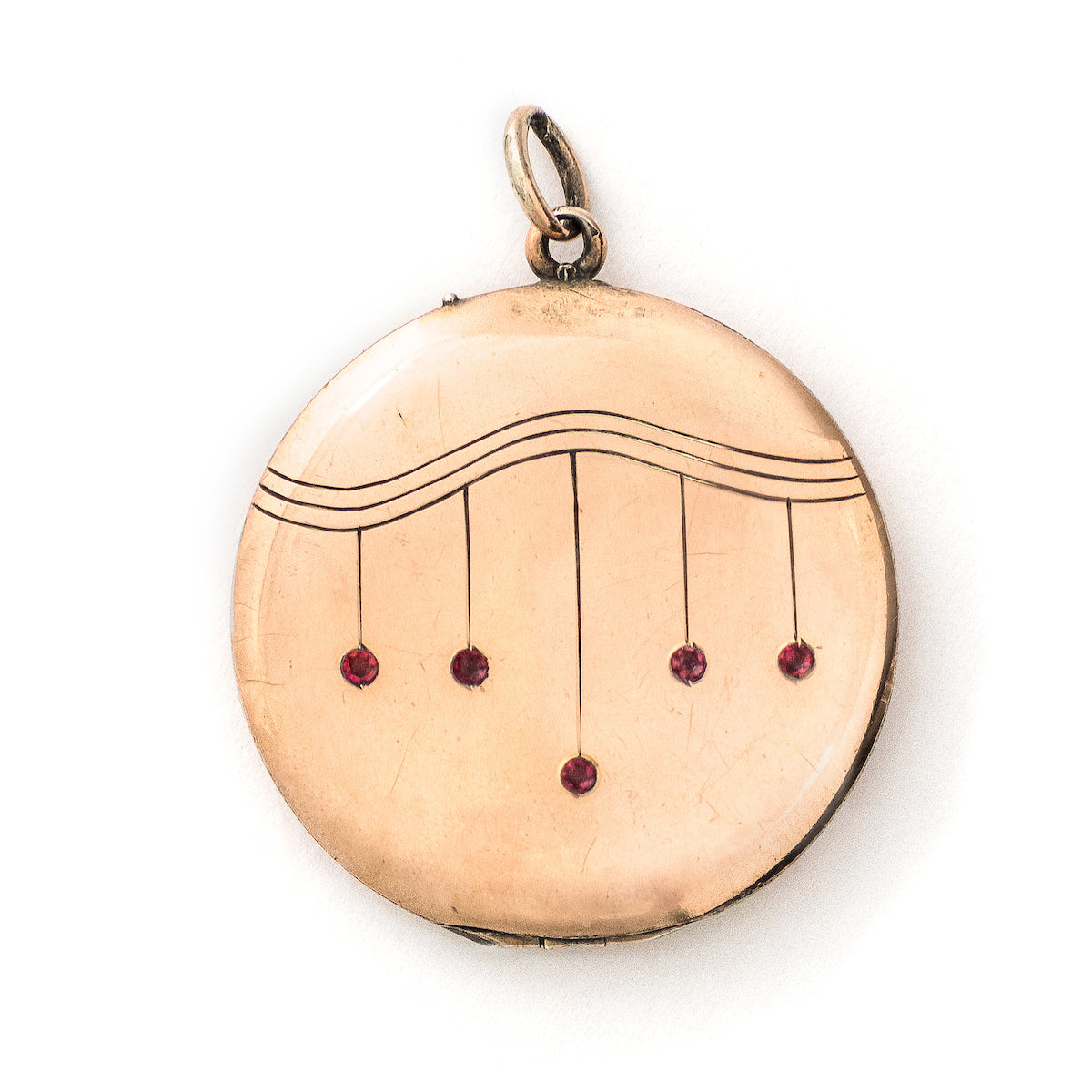 This striking round locket features red stones in a pleasing art deco style pattern. It opens to hold two photos and pairs perfectly with one of our antique gold fill chains.  Front locket view