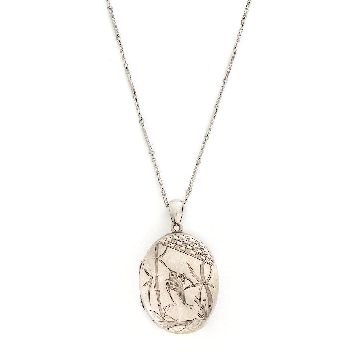 This large oval sterling silver locket features a finely etched swallow and bamboo scene, complete with rolling hills in the back drop. It opens to hold two photos and pairs perfectly with one of our antique sterling silver chains. Front locket view