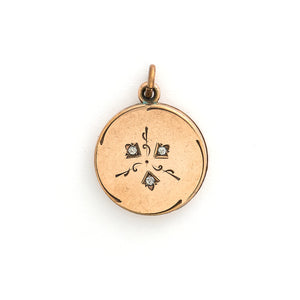This simple round slide locket features 3 white glass stones and a minimalist thirds design. It slides opens to hold two photos and pairs perfectly with one of our antique gold fill chains.  Front locket view