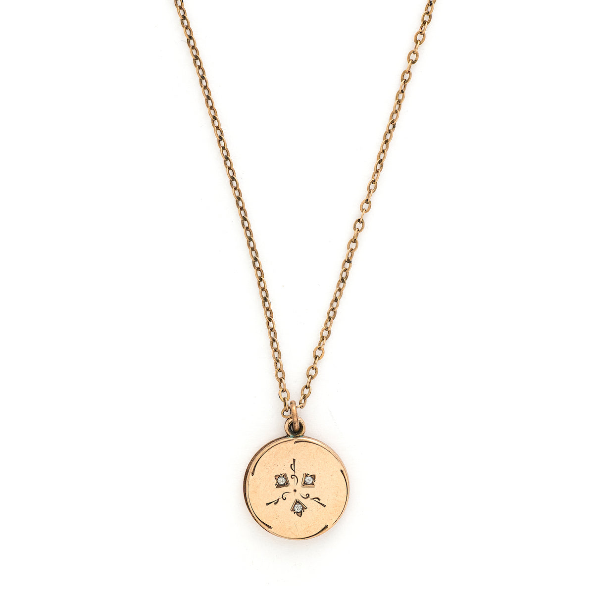 This simple round slide locket features 3 white glass stones and a minimalist thirds design. It slides opens to hold two photos and pairs perfectly with one of our antique gold fill chains.  Front locket view