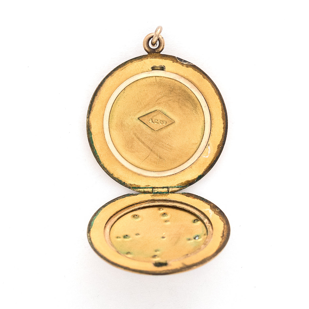This matte round locket features a playful pinwheel design with white and grey glass stones scattered throughout. The initials CAI are inscribed on the back, it opens to hold two photos, includes both original frames and pairs perfectly with one of our antique gold fill chains. Open locket view
