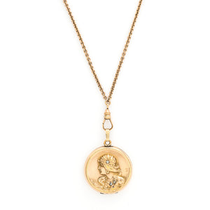This round locket features a woman's profile in raised relief. Her head piece and necklace are adorned with white glass stones and compliment other intricate details such as her earrings and flowing long hair. It opens to hold two photos, includes one original frame and pairs perfectly with one of our antique gold fill chains. Front locket view on chain