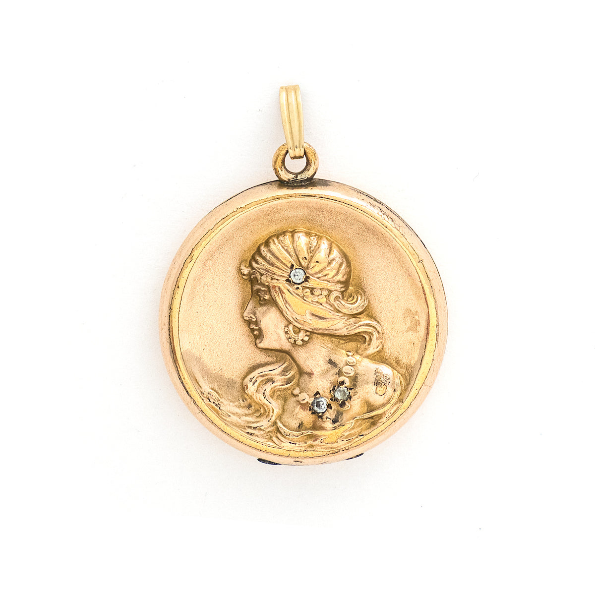 This round locket features a woman's profile in raised relief. Her head piece and necklace are adorned with white glass stones and compliment other intricate details such as her earrings and flowing long hair. It opens to hold two photos, includes one original frame and pairs perfectly with one of our antique gold fill chains. Front locket view