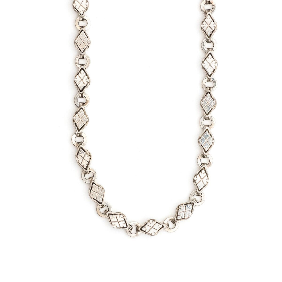 This Victorian-era chain is made of solid sterling silver and features intricately engraved horizontal diamond shapes interspersed with flat circular rings. Paired with a silver or silver and gold locket, this chain instantly makes a necklace more bold and eye-catching.  Full chain view
