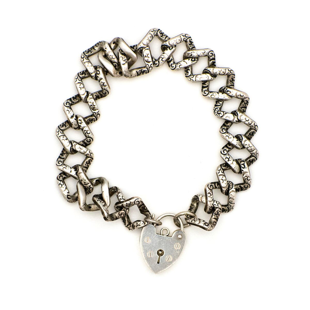 This Vintage Silver Lock Bracelet features a heart shaped lock that is able to open, on a 7" curb chain. On one side of the chain are hand engraved markings, giving the bracelet an edgy feel. Worn simply on its own or made into a statement piece by adding charms, this bracelet has many possibilities. Front bracelet view